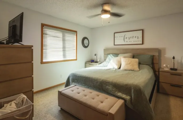 Basement bedroom with a bed, dresser and a window