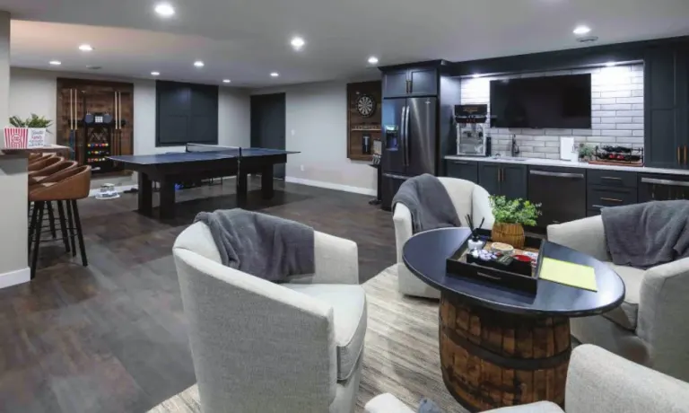 Basement lounge with a game table, bar seating and armchairs