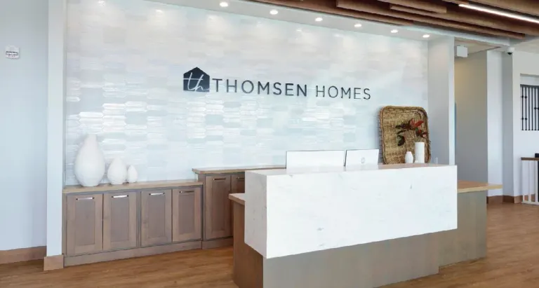 Reception desk with wood cabinetry in front of a light tile wall