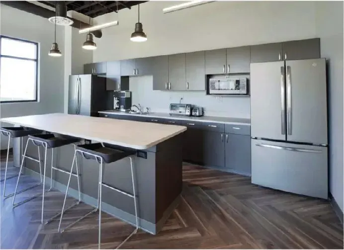 Office kitchen with luxury vinyl plank flooring, a counter and bar stools