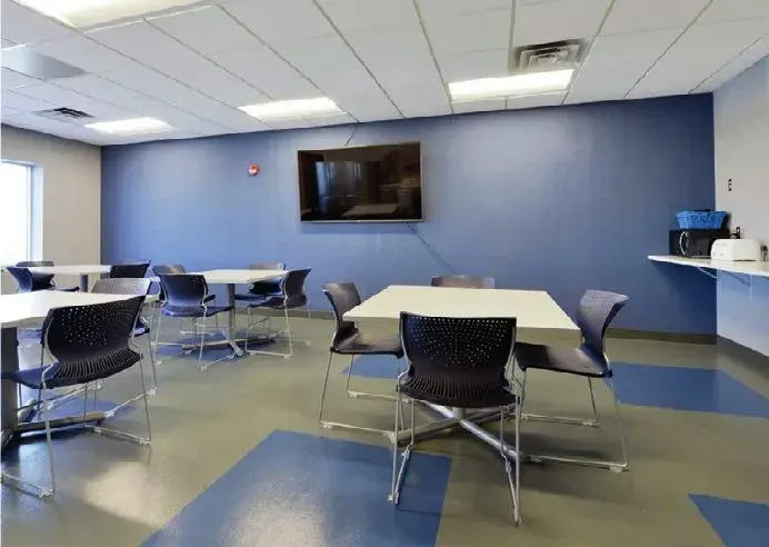 Common area with tables, chairs and blue sheet vinyl flooring