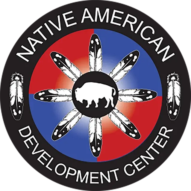 Native American Development Center circular logo with a central bear, feather spokes, red-blue background, black border.