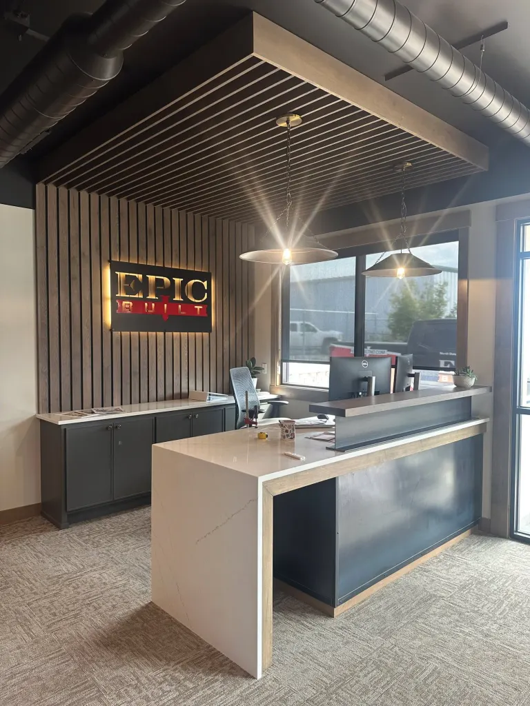 Reception desk with a white counter, navy front and a slatted wood wall behind it