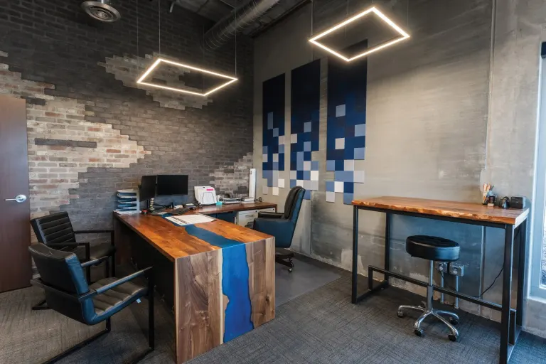 Desk with a walnut top and blue river inlay beside a standing-height table