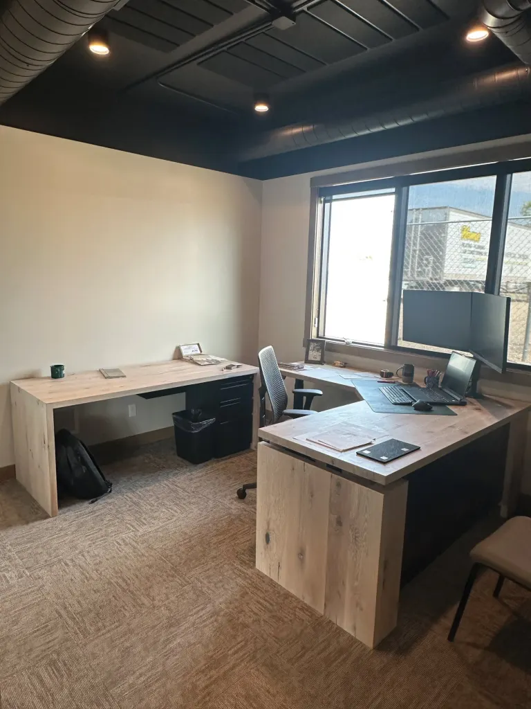Wraparound wood desk in a corner office with a window