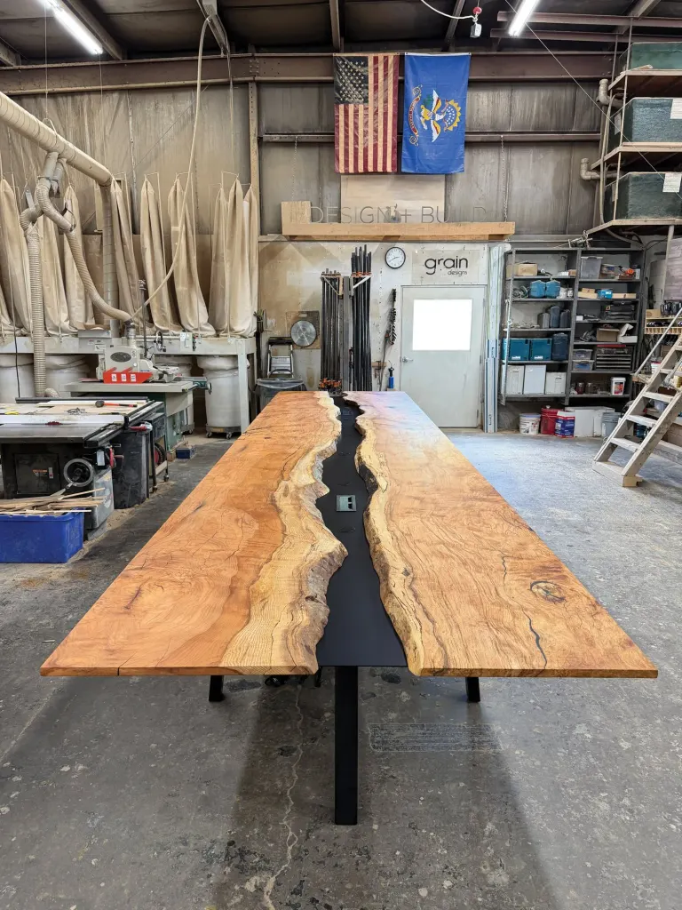 Live-edge wood table with a black river down the middle in a woodworking shop