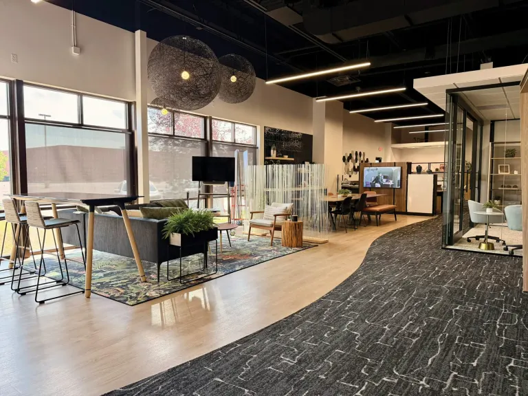 Wide view of the open showroom with a seating area, high-top chairs, round pendant lights and a curving carpet path