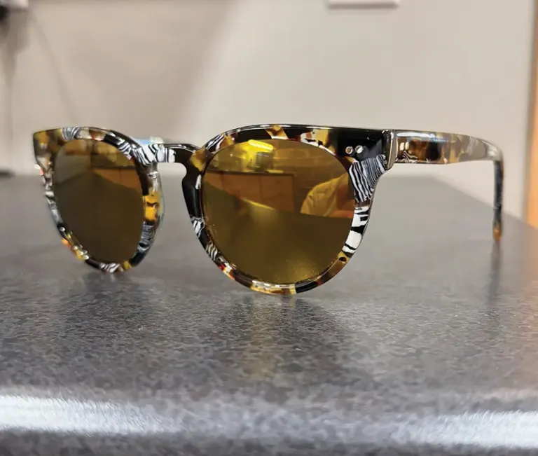 Pair of tortoiseshell sunglasses with amber lenses resting on a gray surface.