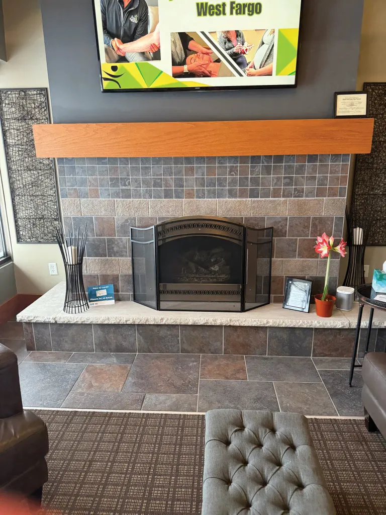 Waiting area with a stone fireplace, a cushioned bench and a wall-mounted screen