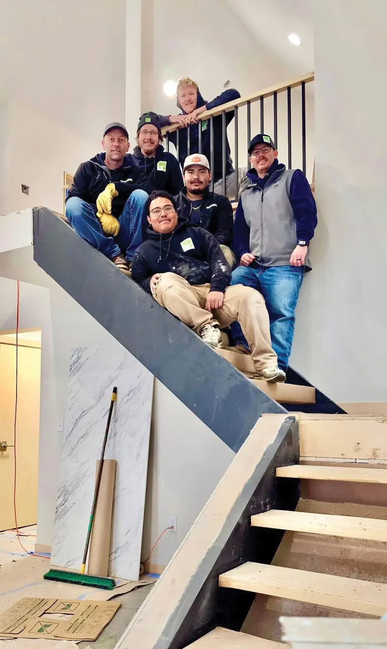 Construction crew posed together on a staircase inside a building under construction