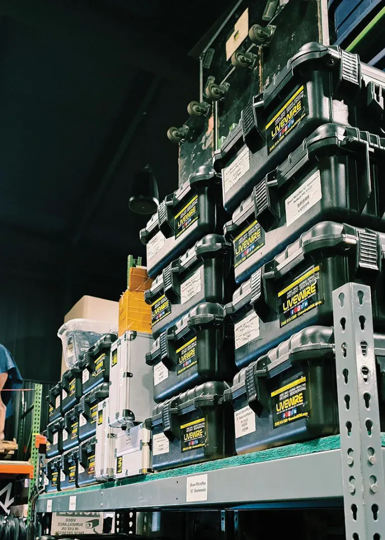 Stacks of black tool cases labeled "Livewire" on industrial shelving in a workshop.